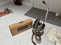 Canister vacuum with hose, wand, storage box, dust bags visible