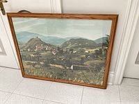 Full view of framed landscape print leaning against wall