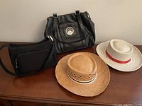 Group shot: two straw hats plus two black handbags on wooden surface