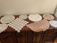 All nine crocheted cotton doilies displayed on dresser