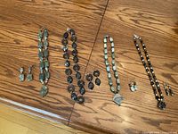 All four necklaces with corresponding earrings displayed on wooden surface