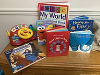Group shot of all books and VTech steering wheel on wooden surface