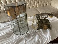 Telephone, glass curio cabinet, pair of silver figurines displayed together