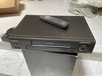 Panasonic PV-7412 VCR with remote and cables on top