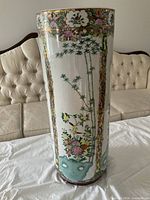 Full view of porcelain cylindrical vase on table showing overall form and decoration
