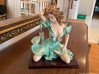 Front view of Santini porcelain figurine on wood base with tag attached