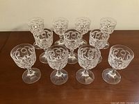 Full set of 11 crystal wine goblets arranged on table showing overall condition and pattern