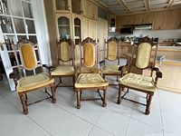 Front view of all six carved wood chairs showing upholstery and design