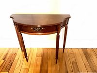 Front view of cherry demilune console table showing drawer and legs