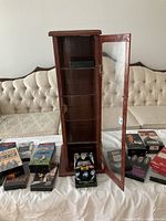 Wooden storage cabinet open, shelves visible, some tapes around