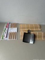 Group view of two sushi mats, packaged chopsticks and steel grater