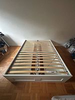 Full view of white queen bed frame with slatted base installed