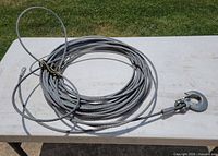 Coiled steel winch cable with hook shown on table