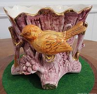 Mauve tree-trunk ceramic planter with yellow bird relief and scalloped gold-trim rim