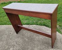 Full view of console table angled, showing top surface and one side panel with stretcher bar