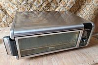 Closed Ninja stainless steel air fry oven on wooden surface