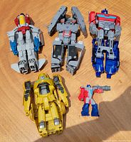 All five Transformers figures laid out showing robot modes