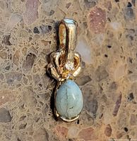 Front view of pendant showing stones and gold-tone setting