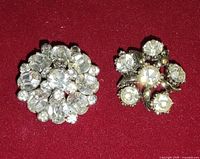 Both rhinestone pendants on red background, showing overall design and condition