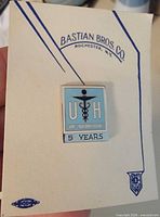 Front view of enamel service pin on original Bastian Bros. Co. card