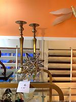 Both brass candlesticks and star sculptures displayed on glass shelf