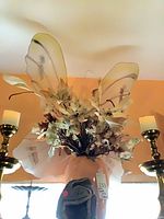 pair of brass candlesticks flanking faux floral vase with geode at base