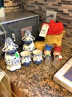 All items grouped on countertop showing cookie jar, four cow planters, graduate shakers and glass shakers