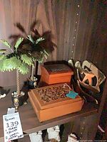 Shelf view with two wooden boxes, brass trivet and metal art pieces