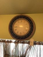 Full view of round wall clock mounted on wall showing overall design and size