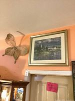 Overall view of framed artwork and butterfly sculpture on wall