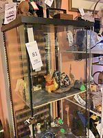 Full view of glass display cabinet with black top and base, showing interior shelves