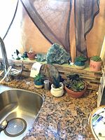 Overview of lot on countertop showing sink, crystal, plaque, faux succulents, bottles and knobs