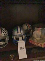 Three loose mini helmets and boxed helmet on shelf