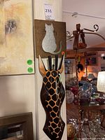 Both plaques mounted vertically; square cat plaque above elongated giraffe head plaque with hooks