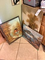 Group shot of three framed paintings leaning against wall