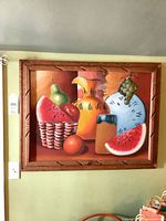 Carved wood framed painting of fruit and pottery on wall