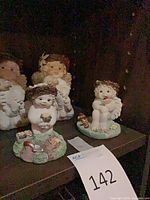 Four small resin cherub angel figurines displayed on shelf