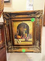 Front view of framed still life painting in ornate gold frame