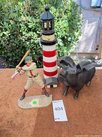 Three figurines grouped together: baseball player, lighthouse, winged pig