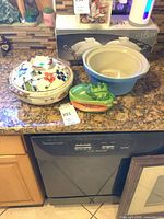 Overview of all three ceramic pieces on countertop: floral casserole, blue bowl, vegetable-shaped server