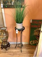 Full view of wrought iron plant stand with pot and faux plant