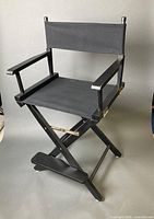 Front view of black folding director chair showing seat and arms