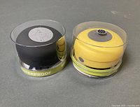 Both speakers in packaging, showing colors and waterproof label