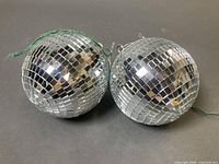 Two 6 inch mirror disco balls side by side showing reflective surfaces and green cords