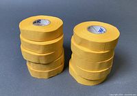 Two stacks of five yellow cloth tape rolls (total 10)
