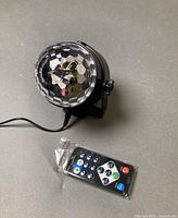 Mini disco ball light with sealed remote on surface