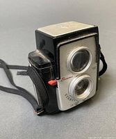 Front angled view of Kodak Brownie Starflex camera showing lenses, nameplate, and strap