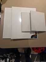 Four blank white canvases stacked showing two larger and two smaller sizes