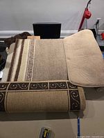 Rolled mats showing beige bath mat, striped mat, brown runner