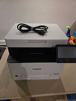 Front view of Canon MF653Cdw printer with power cord on top and touchscreen panel